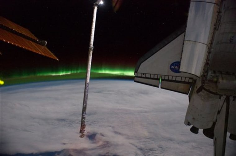 In this July 14, 2011 photo provided by NASA, Aurora Australis, or the Southern Lights, light up the Earth's horizon as seen from the International Space Station, looking past the docked space shuttle Atlantis' cargo bay and part of the station including a solar array panel, as the joint complex passed over the southern hemisphere. (AP Photo/NASA)